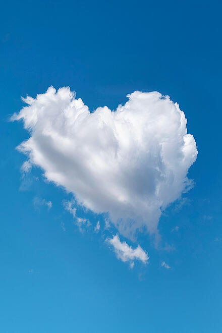 Eine weiße Wolke in Herzform schwebt am klaren blauen Himmel.