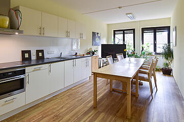 Große moderne helle Küche mit großen Holztisch und Stühle im Johanniterhaus Bonn.