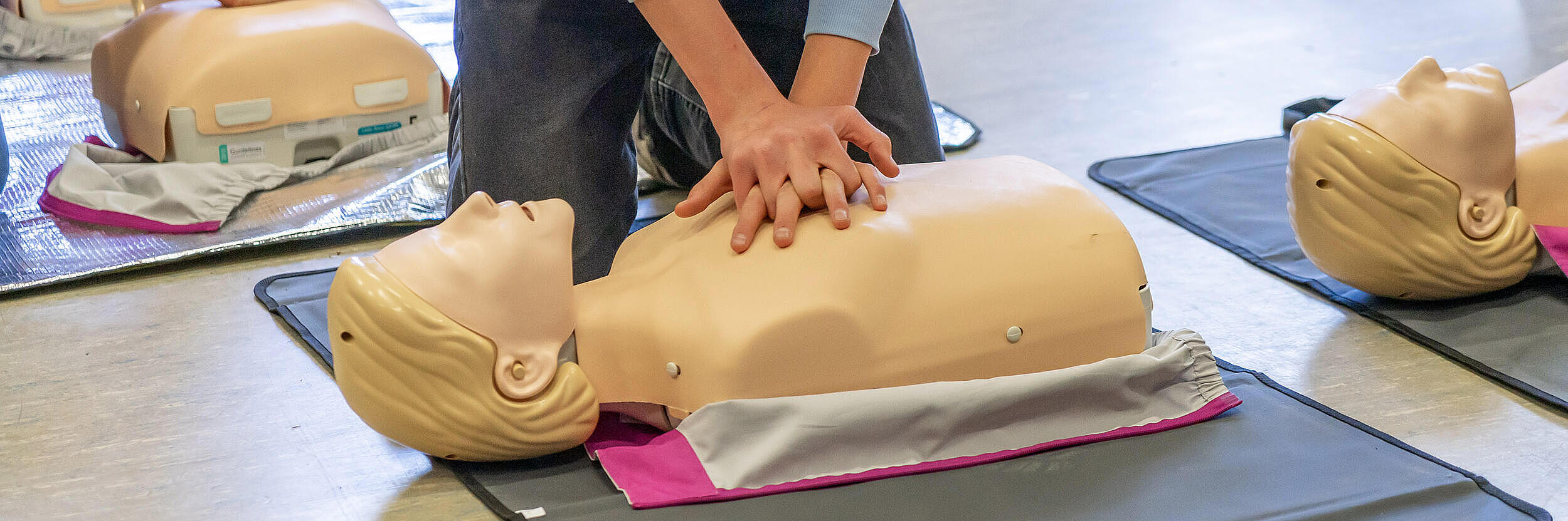 Eine Person führt eine Herzdruckmssage an einer Puppe durch.