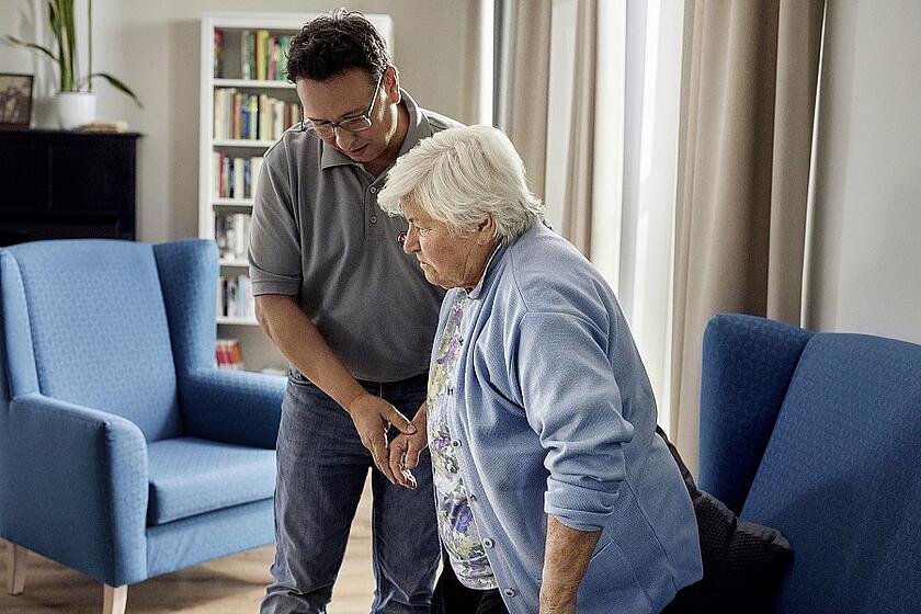 Eine ältere Frau wird von einem Johanniter-Mitarbeiter gestützt