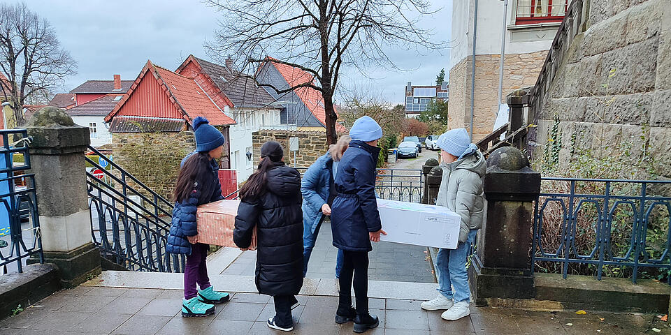 Kinder tragen Pakete eine Treppe hinab.