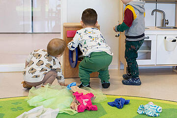 Drei Kinder spielen gemeinsam mit einer Spielzeugküche