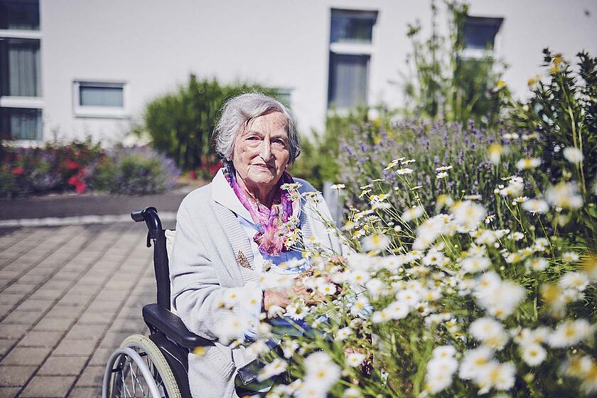 Eine Bewohnerin genießt den Duft der Blumen