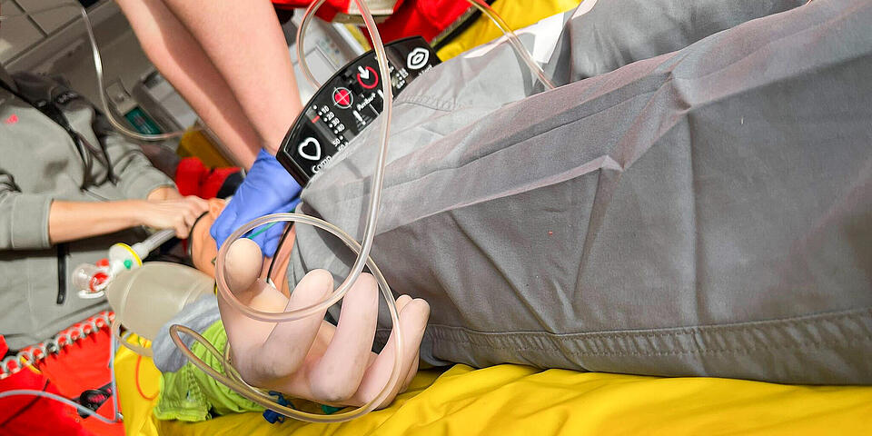 An einer Übungspuppe sieht man Hände, die eine Reanimation durchführen.