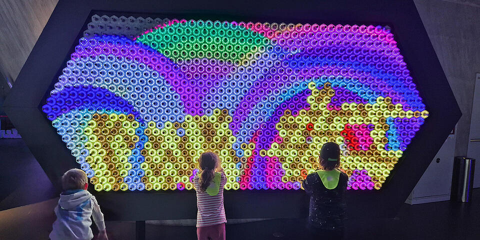Kinder vor einem großen bunten Lichtexponat