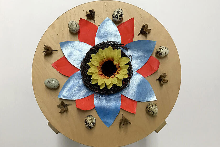 Pappvolage bereits kreativ gestaltet mit einer Sonnenblume, farbigen Blättern und Wachteleiern. 