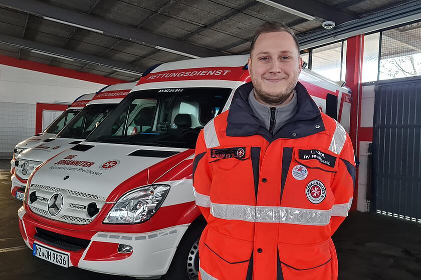 Notfallsanitäter vor Rettungswagen in Fahrzeughalle